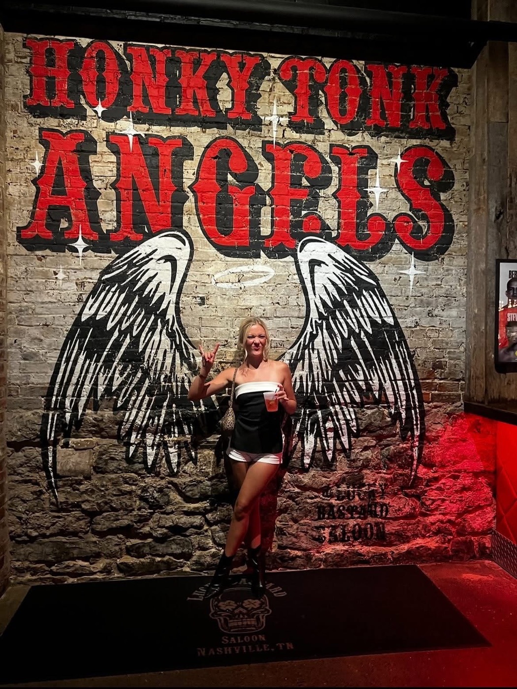 A Broadway Betties posing beneath the Honky Tonk Angels mural